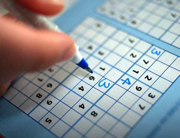 Person fills in sudoku puzzle with a pen
