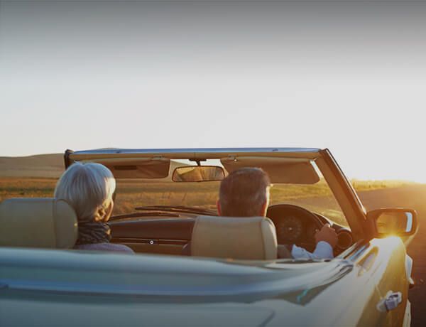 Two people driving in convertible with top down