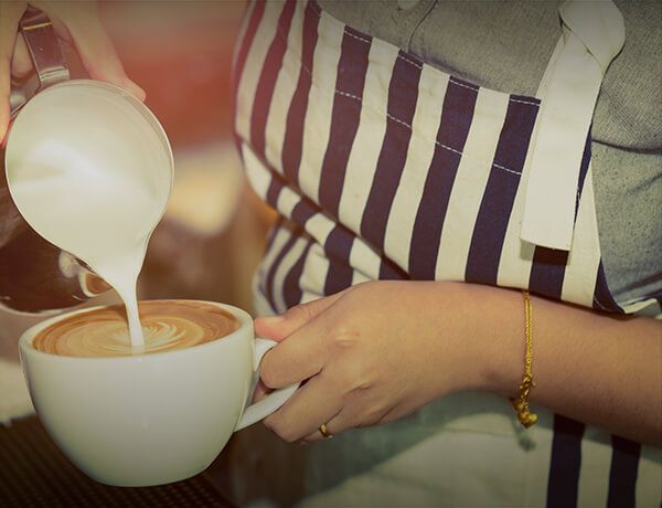 Barista pouring milk into a latte coffee drink